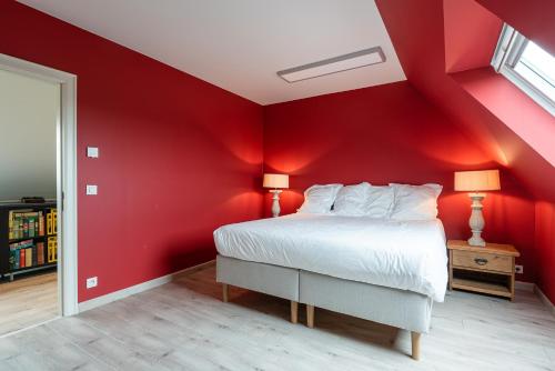 a bedroom with red walls and a bed with two lamps at Polderwoning 'Cleylantshof' in Sint-Laureins