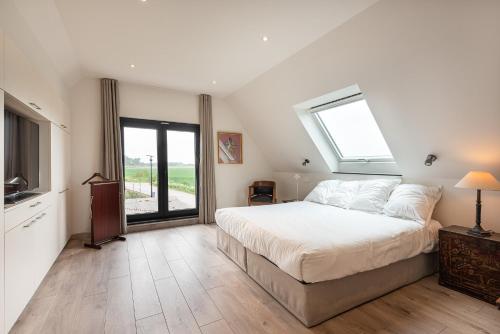 a bedroom with a large bed and a window at Polderwoning 'Cleylantshof' in Sint-Laureins