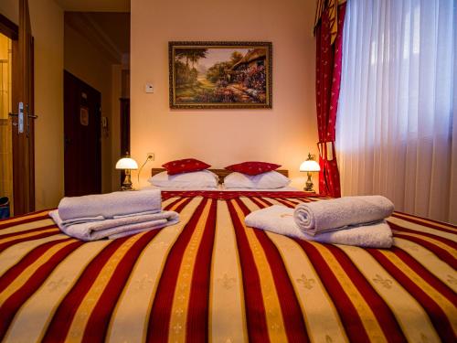 a bedroom with a striped bed with towels on it at Pensjonat Zbójecki Dwór - ATRAKCYJNY PAKIET ŚWIĄTECZNY - blisko basenów termalnych i szlaków górskich in Bukowina Tatrzańska