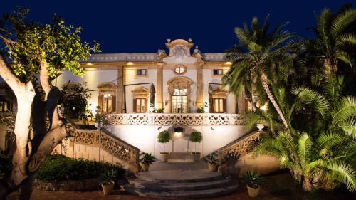 a building with stairs and palm trees at night at Holiday home La Rinascita in Bagheria