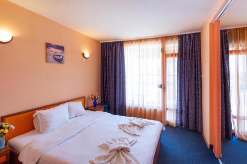 a hotel room with a large bed and windows at Family Hotel Jemelly in Obzor