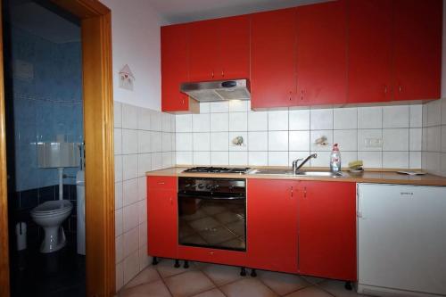 - une cuisine rouge avec évier et cuisinière dans l'établissement Nina, à Pula