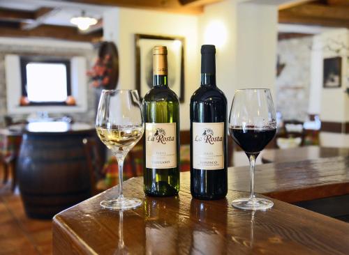 two bottles of wine sitting on a table with two glasses at Agriturismo La Rosta in Cervignano del Friuli