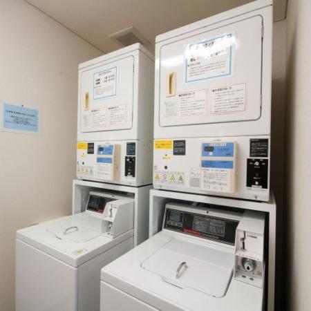 a laundry room with three machines and certificates on the wall at Super Hotel Izumo Ekimae in Izumo