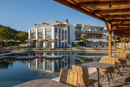 a pool with chairs and tables and a building at Atalanti Boutique Hotel - Adults Only in Faliraki