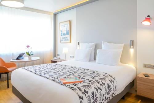 a hotel room with a large white bed and a chair at Mercure Marseille Centre Prado Vélodrome in Marseille