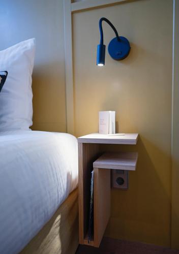a bedroom with a bed and a nightstand with a blue lamp at The Times Hotel in Amsterdam