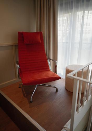 a red chair sitting in a room next to a bed at The Times Hotel in Amsterdam