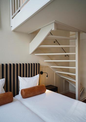 a bedroom with a white bed and a staircase at The Times Hotel in Amsterdam