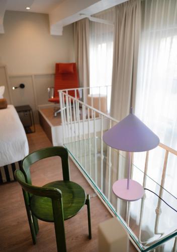 a glass table with a chair and a lamp in a room at The Times Hotel in Amsterdam