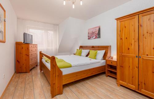 a bedroom with a wooden bed and a television at Hotel Landgasthof Hölzer in Fröndenberg
