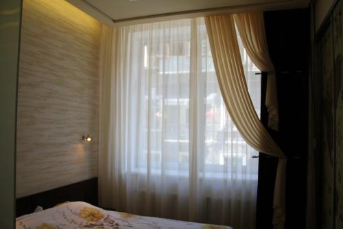 1 dormitorio con 1 cama y una ventana con cortinas en Apartment in Center of Odessa, en Odessa