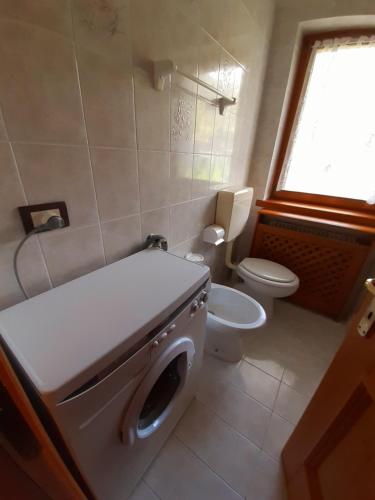 a bathroom with a washing machine and a toilet at CasaSabry in San Nicolò di Comelico