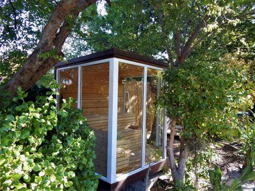 a wooden greenhouse in a garden with a tree at Khashamongo B & B in Somerset West