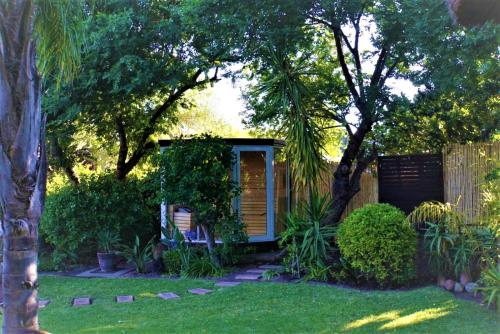 a garden cabin with a chair in the yard at Khashamongo B & B in Somerset West