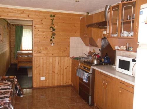 a kitchen with wooden cabinets and a stove top oven at Під лісом у гіда in Yaremche