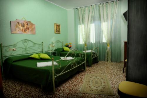 a bedroom with two green beds and a window at Maison De Lussy in Piazza Armerina