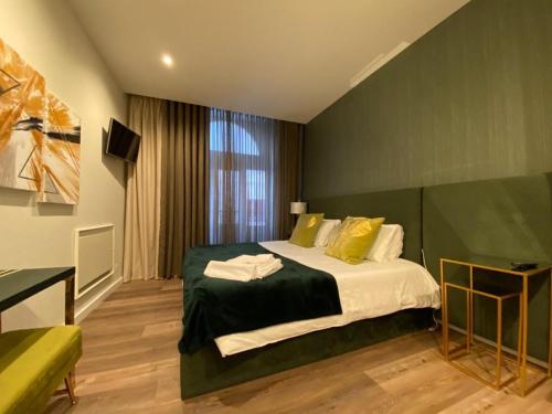 Junqueira76 Guesthouse في بوفوا دي فارزيم: غرفة نوم بسرير مع جدار أخضر