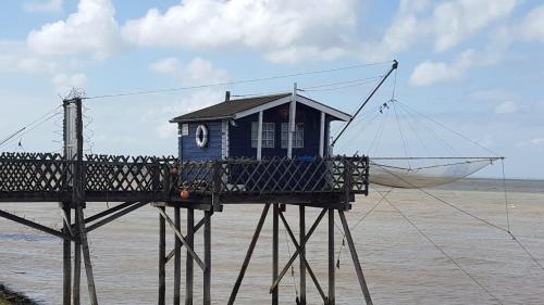une petite maison bleue sur un support dans l'eau dans l'établissement La Pointe du Soleil, au Le Verdon-sur-Mer