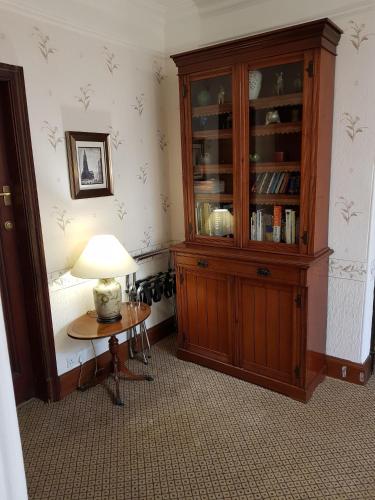 a room with a wooden hutch and a table with a lamp at Hamilton House in Dumfries