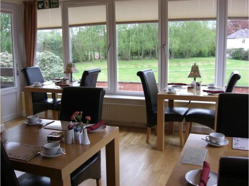 a restaurant with tables and chairs and a large window at Hamilton House in Dumfries