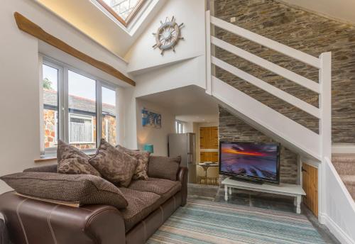 a living room with a couch and a tv at The Old Coach House in Boscastle