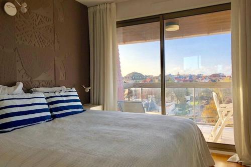 a bedroom with a bed and a large window at Appartement triangle d'or terrasse garage fermé in Le Touquet-Paris-Plage