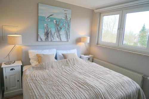 1 dormitorio con 1 cama con manta a rayas y 2 ventanas en Haus Ruh di ut Wohnung LUV, en Kellenhusen