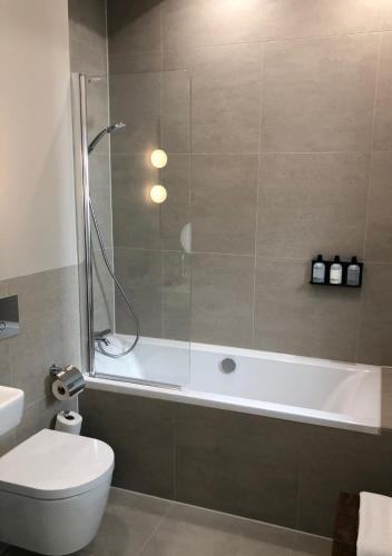 a bathroom with a shower and a toilet and a tub at The Times Hotel in Amsterdam