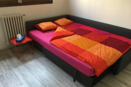 - un lit avec une couette colorée et une table de chevet dans l'établissement Studio proche du lac-Triangle d'or, à Annecy
