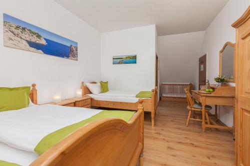 a bedroom with two beds and a desk and a table at Hotel Landgasthof Hölzer in Fröndenberg