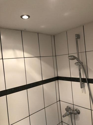 a shower with white tiles and a shower head at B OUR GUEST at Your cozy hideaway Dome near Dresden in Frauendorf