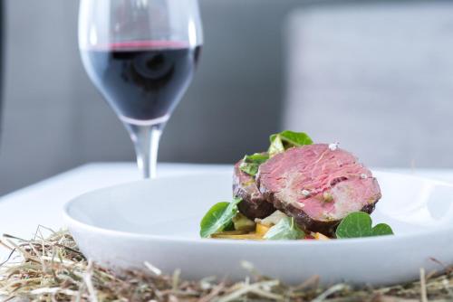 a plate of food and a glass of red wine at Rowhill Grange Hotel & Utopia Spa in Dartford