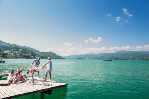 a group of people on a dock in the water at Boutiquehotel Caravella Velden by S4Y in Velden am Wörthersee