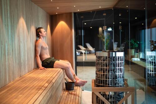 a man sitting on a bench in a room at Hotell Södra Berget in Sundsvall