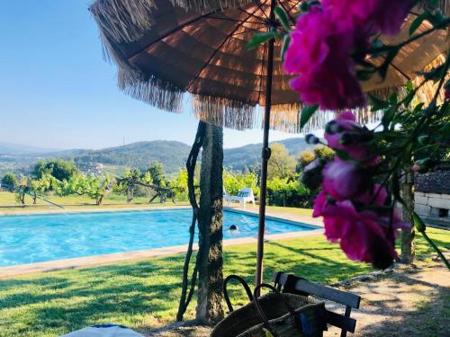 a bench with an umbrella and a swimming pool at Casa da Ventozella in Penafiel