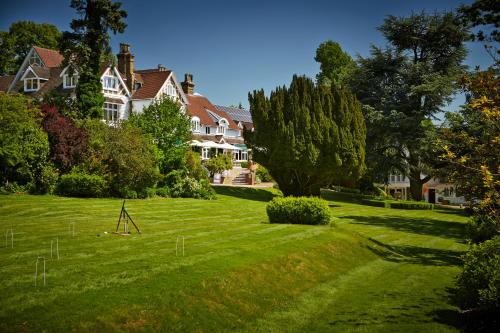 a large house on a green lawn with trees at Rowhill Grange Hotel & Utopia Spa in Dartford