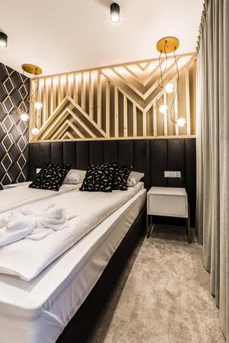 a bedroom with a large bed with a wooden wall at Aparthotel Prestige & SPA in Zakopane