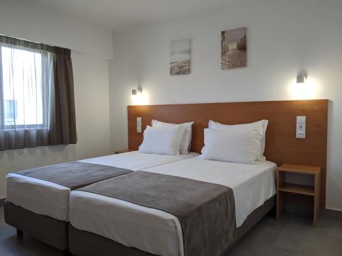 una camera da letto con un grande letto con lenzuola bianche di Bayside Salgados ad Albufeira