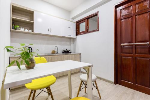 a kitchen with a white table and yellow chairs at Dlux Saigon in Ho Chi Minh City