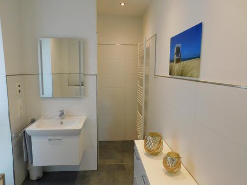 a white bathroom with a sink and a mirror at Erdgeschoss Wohnung Watt'n Meer mit Garten in Dangast in Varel