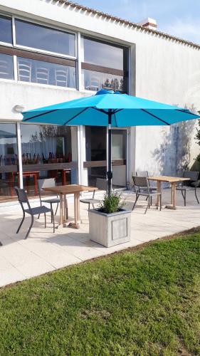 a picnic table with a blue umbrella in front of a building at Hotel Les Esseppes in LʼÉpine