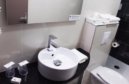a bathroom with a white sink and a toilet at The Originals City Hôtel, Aéroport Beauvais in Beauvais
