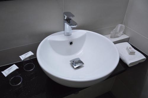 a white sink with a faucet on top of it at The Originals City Hôtel, Aéroport Beauvais in Beauvais