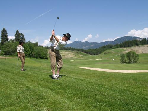 dos hombres jugando golf en un campo de golf en Hotel Gasthof zur Linde en Mariahof