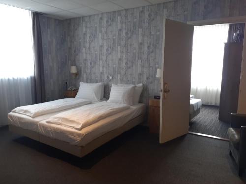 a bedroom with a bed with white sheets and pillows at Grand Hotel Monopole in Valkenburg