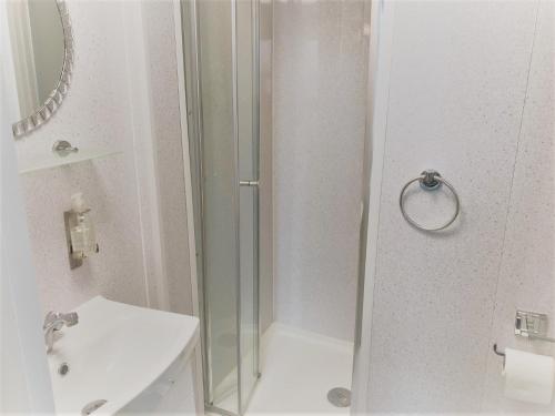 a white bathroom with a shower and a sink at The Berkeley Morecambe in Morecambe