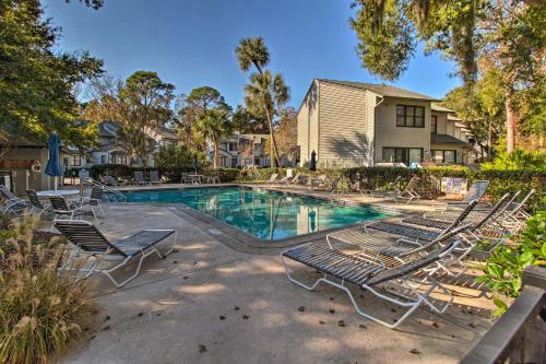 a swimming pool with lounge chairs and a house at Walk to Forest Beach Hilton Head Getaway! in Hilton Head Island