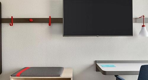 a room with a desk and a tv on a wall at avid hotels - Columbus Northwest - Hilliard by IHG in Hilliard