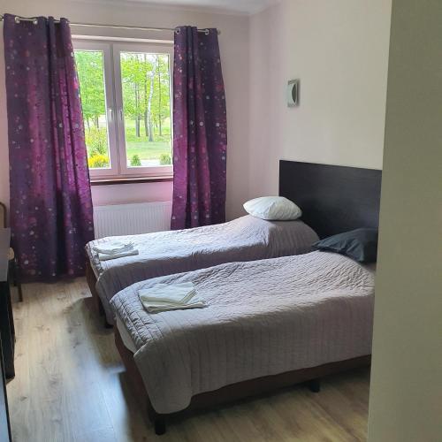 two beds in a room with purple curtains and a window at JURAJSKI OLSZTYN in Olsztyn